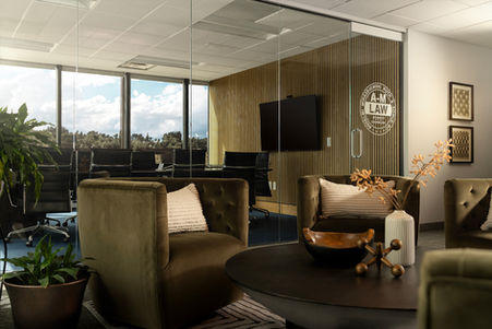 Commercial meeting space with olive green chairs, black coffee table, and adjacent conference room designed by Design Studio Detroit.
