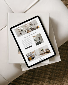 Tablet displaying the Residential Design page of Sol Vibe Design’s website, placed on two design books atop a white leather ottoman with a woven rug beneath, part of a custom website by Cathleen Hall Creative.