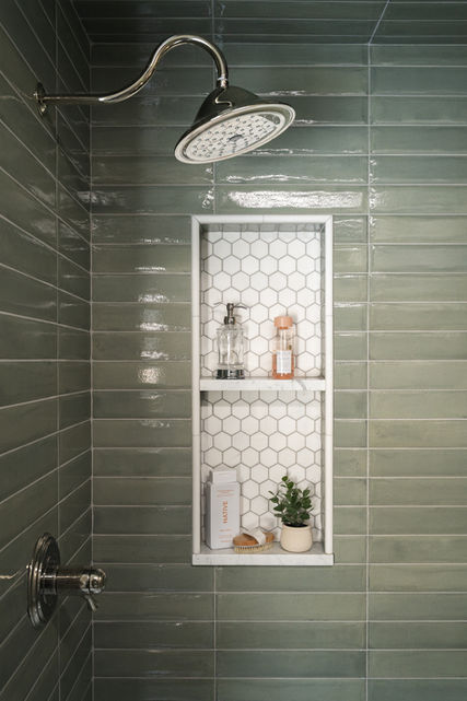 Walk-in shower with olive green tile, chrome fixtures, and built-in storage in a luxury Michigan home