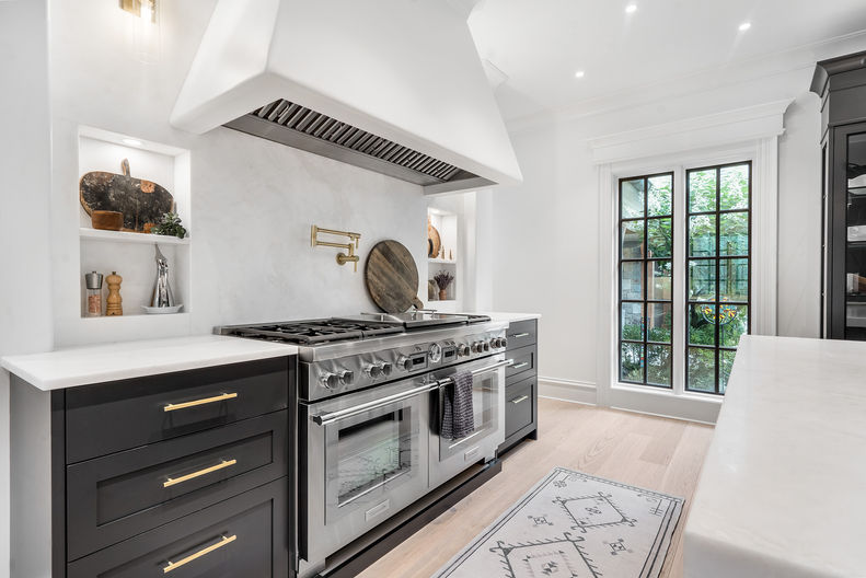 Chef's kitchen with gas range  and bright open lighting and spacing within the kitchen design. 