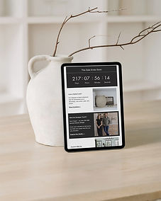 Tablet showing a branded email marketing template for Shop by DNC, leaning against a jug-style vase with a branch, with white built-in shelving in the background, part of the ecommerce and email automation setup by Cathleen Hall Creative.