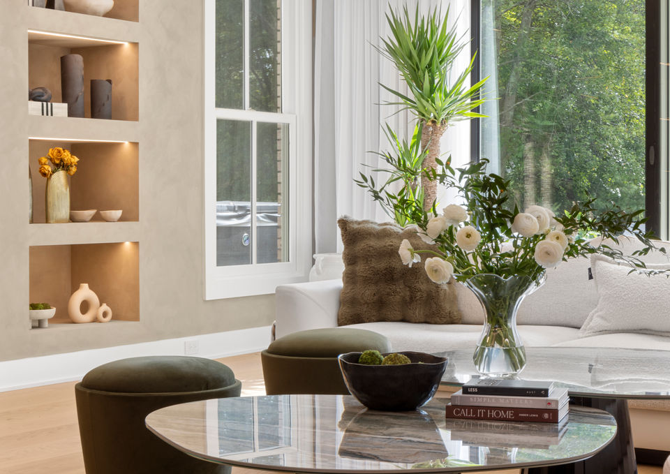 Luxury living room detail with marble coffee tables, olive accent seating, limewashed walls, and built-in LED shelving in a contemporary-modern home.