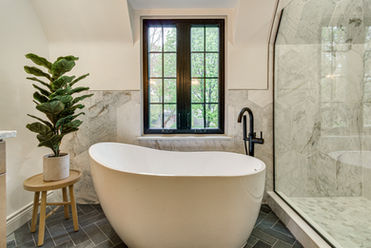 Luxury bathroom featuring marble tile, soaking tub, and walk-in shower designed for a whole home renovation by Design Studio Detroit.