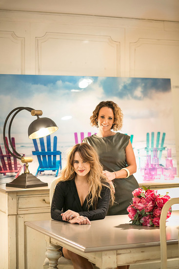 Fotografía profesional de dos mujeres empresarias en oficina creativa, retrato corporativo en interior con decoración moderna y flores sobre el escritorio.