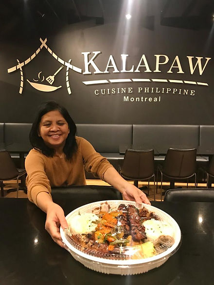 Kalapaw owner serving Kamayan feast tray in front of logo on wall