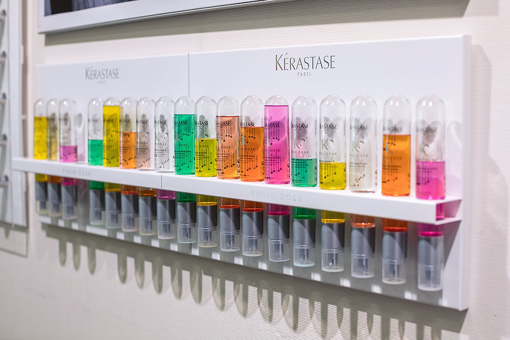 Farbenfrohe Kérastase Haarpflege-Flakons auf einem Regal im Salon.