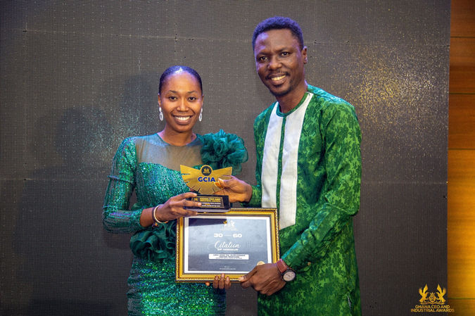 Smiling man and woman hold an award plaque