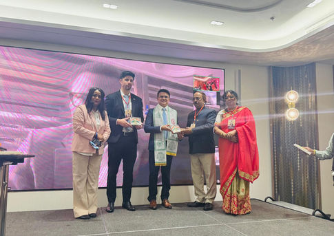 Five people on stage; man receives award at a diplomatic event in Thailand