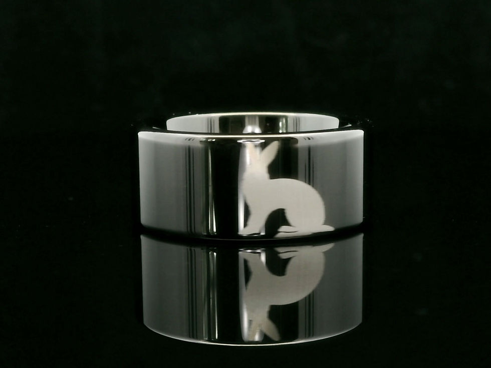 Tungsten wedding band with engraved rabbit silhouette and polished reflective finish, a nature-inspired personalized ring.