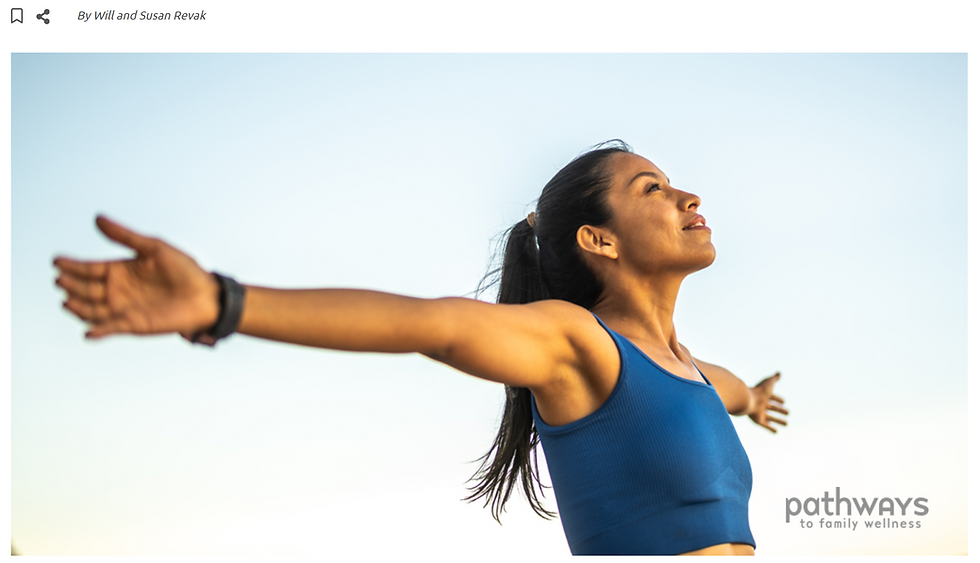 Woman in a blue athletic top standing outdoors with her arms open and her face lifted toward the sky.