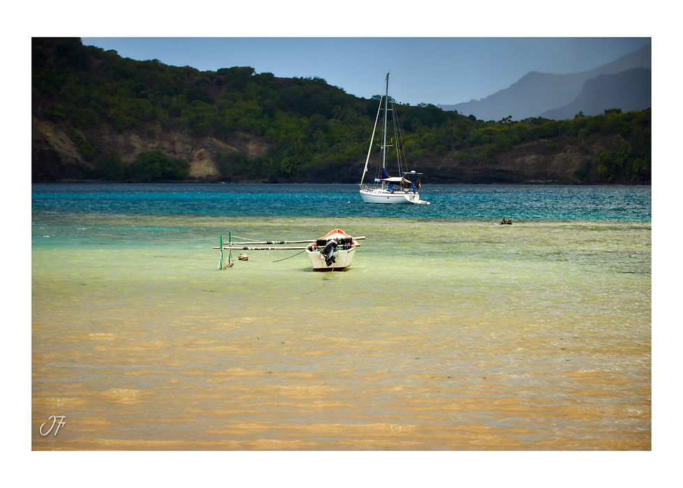 Pirogue à balancier et voilier ancrés dans le lagon de la Baie d'Anaho en Polynésie