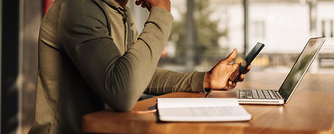 Young man working in his office on a phone and laptop