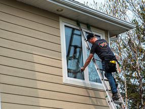 Wes, a professional window cleaner, comfortably cleaning the windows of a 2-storey home from a ladder.