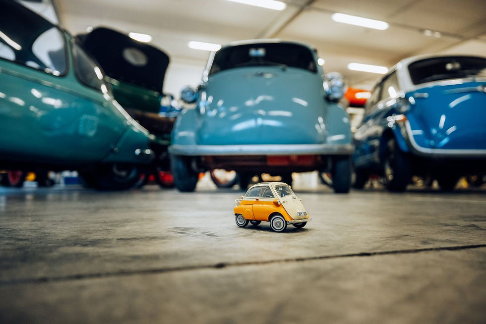 Eine kleine Modell-Isetta steht im Vordergrund auf dem Boden. Dahinter befindet sich eine originale, größere BMW-Isetta.