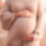 Pregnant woman wearing cozy knitted sweater holding tummy with hands outdoors close up. Mo
