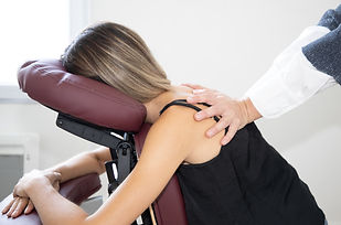 Massage therapist woman massaging female back sitting on massage seated on knee massage ch