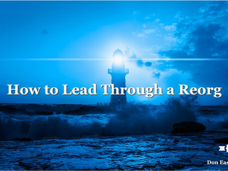 A lighthouse stands in silhouette against a deep blue stormy sky, its beacon shining brightly while powerful waves crash against the rocks at its base. Bold white text reads: "How to Lead Through a Reorg." Don Eash Coaching logo in the lower right corner.