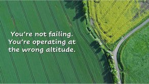 Aerial view of green and yellow fields with winding road representing operating at the wrong altitude in leadership