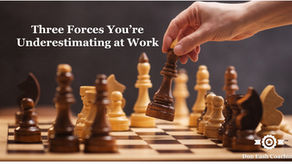 Hand moving a chess piece on a board mid-game representing the forces of self-interest, ego, and competition in leadership