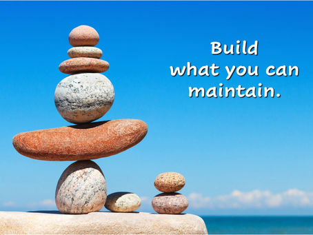 Balanced stones stacked by the ocean representing sustainability and building what you can maintain