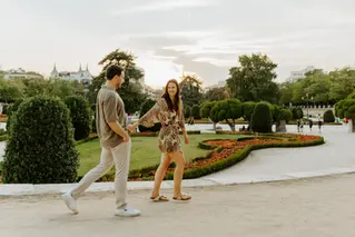 Engaged couple walking near Parterre Gardens paths in Retiro Park

