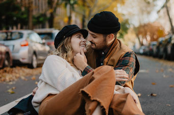 Stylish couple posing in Madrid city streets with elegant outfits and warm colors.