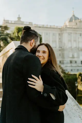 Close-up engaged couple hug with Royal Palace Madrid in background