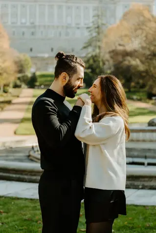 Engaged couple holding hands and smiling in Campo del Moro with the Royal Palace behind