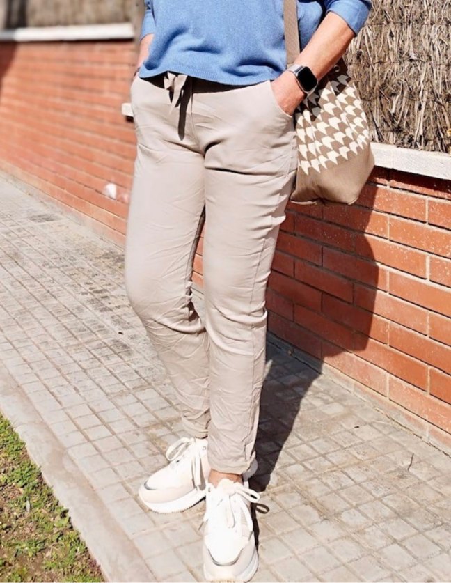 Mujer con pantalones beige, calzado deportivo y bolso