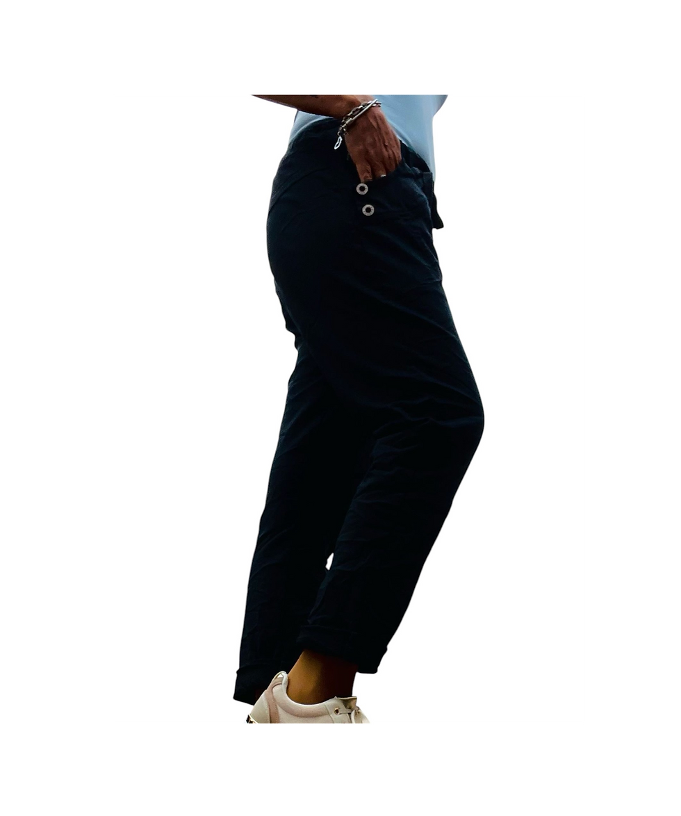 Mujer mostrando pantalones casuales negros elegantes, botones dorados.