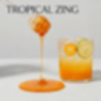 A vibrant, refreshing display showing a glass honey dipper slowly drizzling a golden-orange citrus syrup onto the floor. Besi