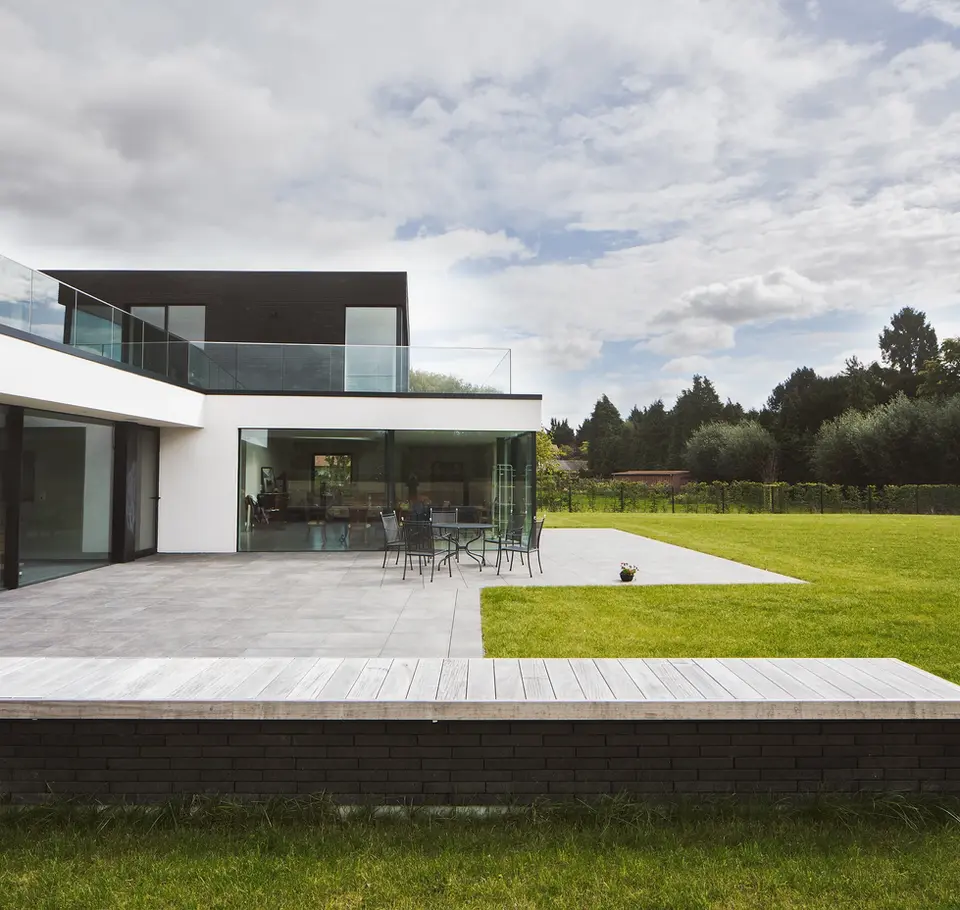 La villa émerge élégamment de son environnement, une structure cubique aux lignes épurées et contemporaines. Les larges fenêtres rectangulaires inondent l'intérieur d'une douce lumière, créant une fusion harmonieuse entre l'intérieur et l'extérieur. L'architecture audacieuse est soulignée par des matériaux modernes. Une résidence à la fois minimaliste et chaleureuse.