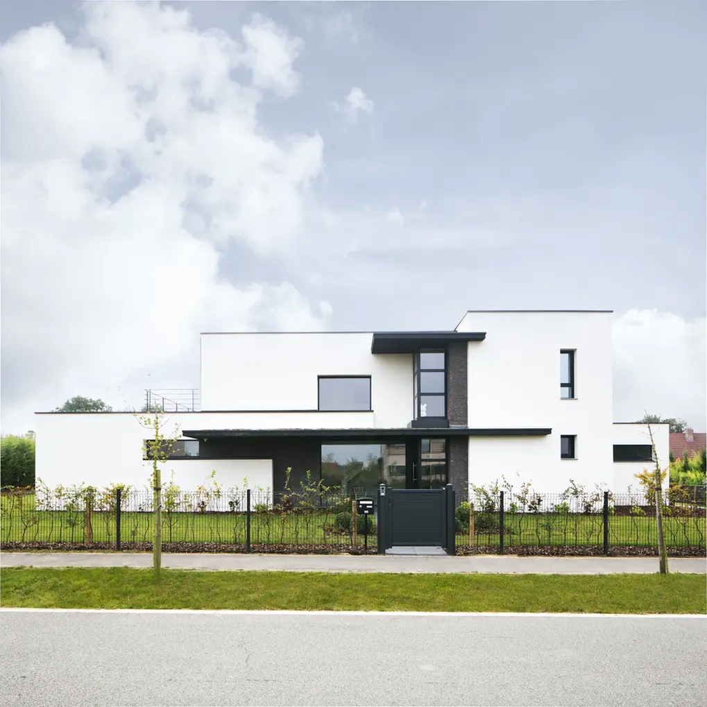 La villa émerge élégamment de son environnement, une structure cubique aux lignes épurées et contemporaines. Les larges fenêtres rectangulaires inondent l'intérieur d'une douce lumière, créant une fusion harmonieuse entre l'intérieur et l'extérieur. L'architecture audacieuse est soulignée par des matériaux modernes. Une résidence à la fois minimaliste et chaleureuse.