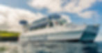 A White Body Glove catamaran anchored near the coast under a partly cloudy sky, awaiting adventure.