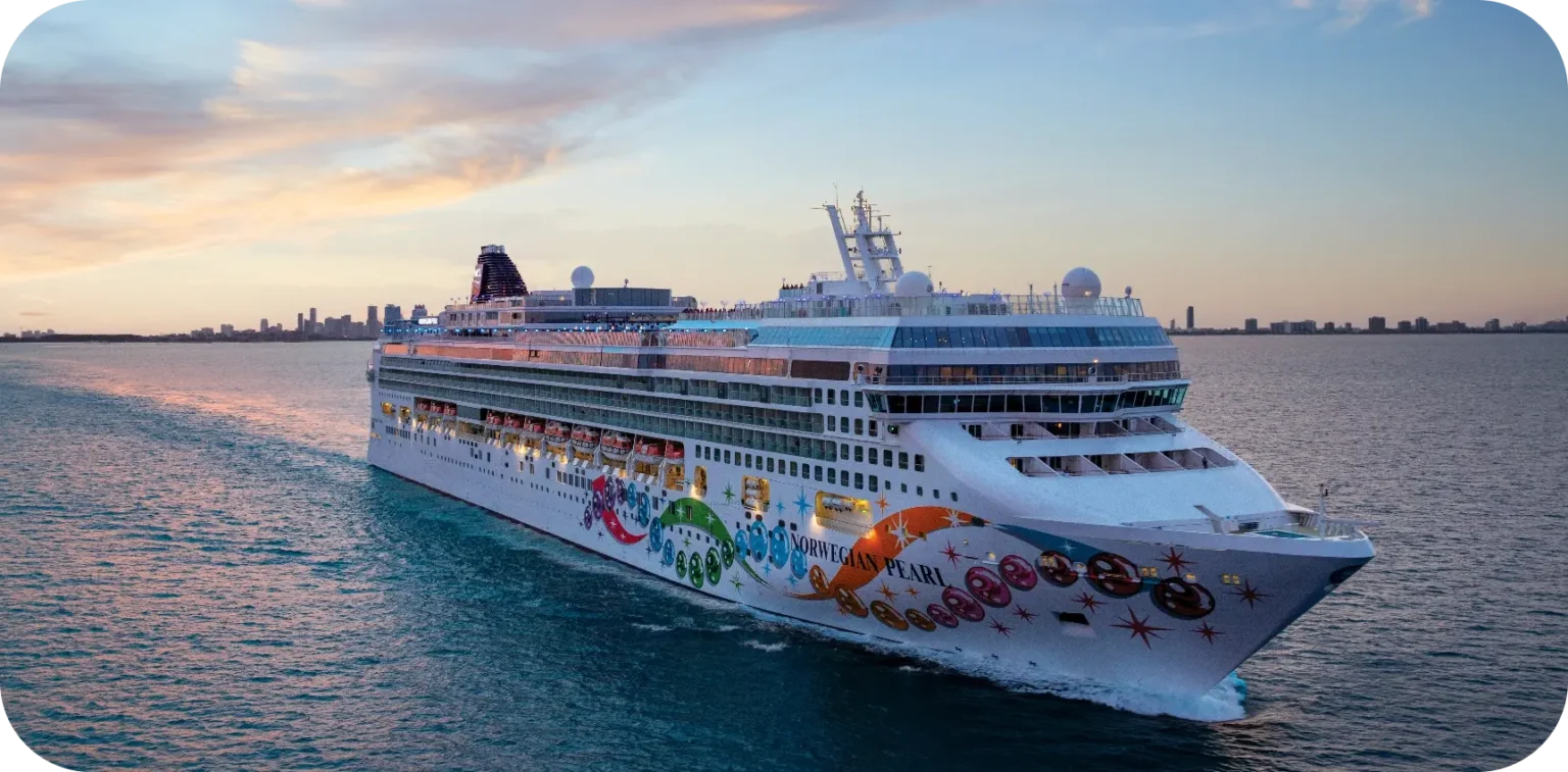 Large ocean going cruise ship with colorful designs on white floating on calm ocean at sunset