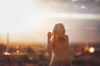 blonde woman playing with her hair in front of a sunset
