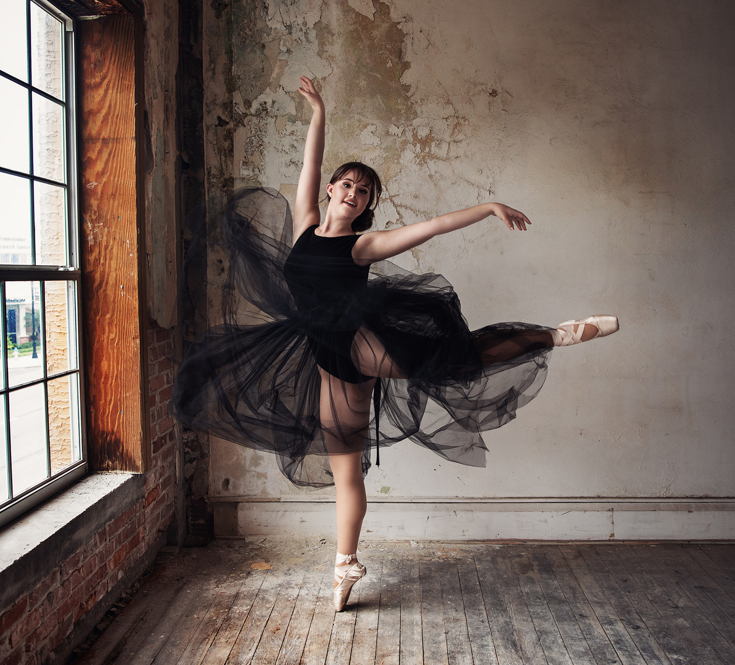 ballerina in black dress posing for the camera inside a studio