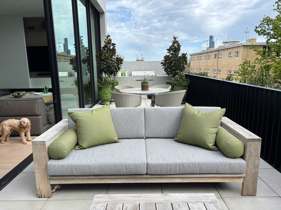 Outdoor patio with gray sofa and green cushions.