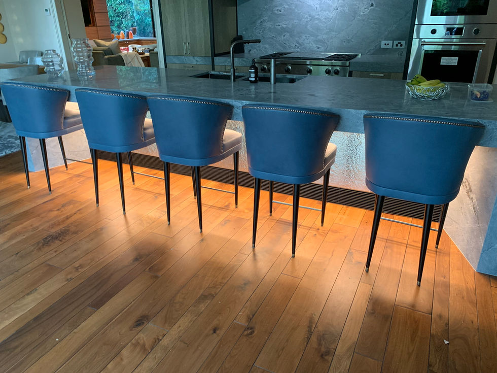 Modern kitchen with blue bar stools and wooden floor.
