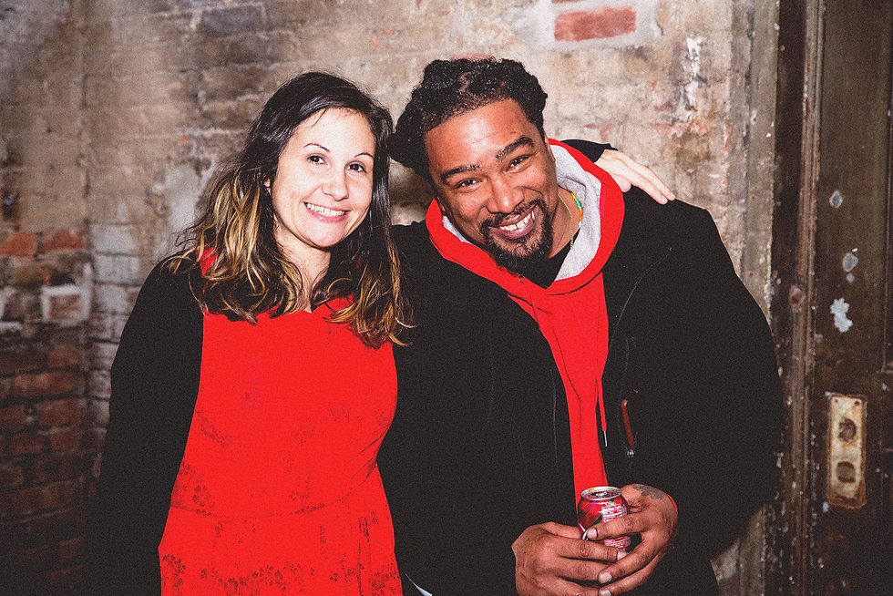 Man and woman smiling, wearing red, lookg at the camera, at an event.