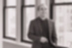 Man in suit jacket smiling and looking at the camera.