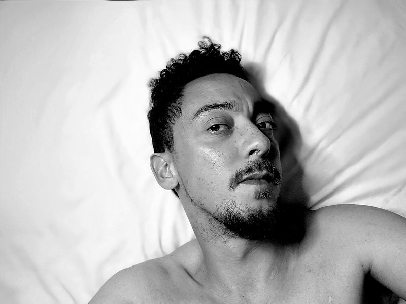 Male escort lying on a bed.