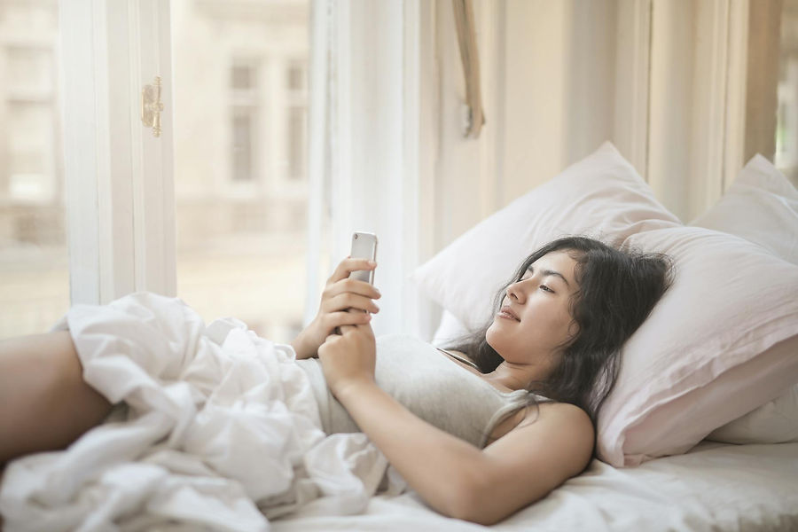 Young woman in bed using her phone.