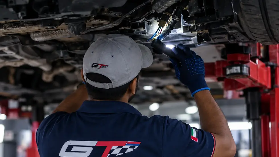 mechanic inspecting underbody wiring with torch under raised car