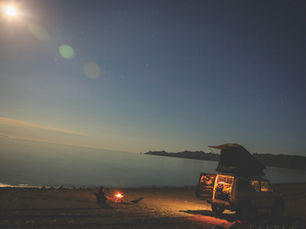 A camper and a campfire on a deserted beach