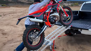 A rider loads a motorcycle into a pickup truck using the Stockton folding motorcycle ramp