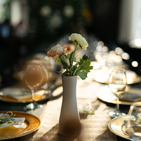 Elegant table setting with flowers and wine glasses, prepared for a catered event.
