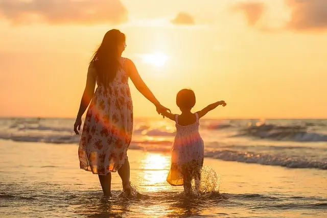 little girl and her mom holding hands on a sunny seashore