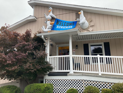 The entrance of a building with three seagull sculptures holding a blue banner that reads "welcome, bienvenidos" above it. 