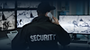Security officer monitoring surveillance screens on phone in hand